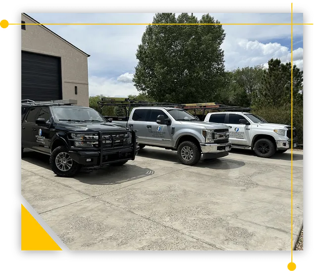 Three trucks are parked in a parking lot in front of a building.